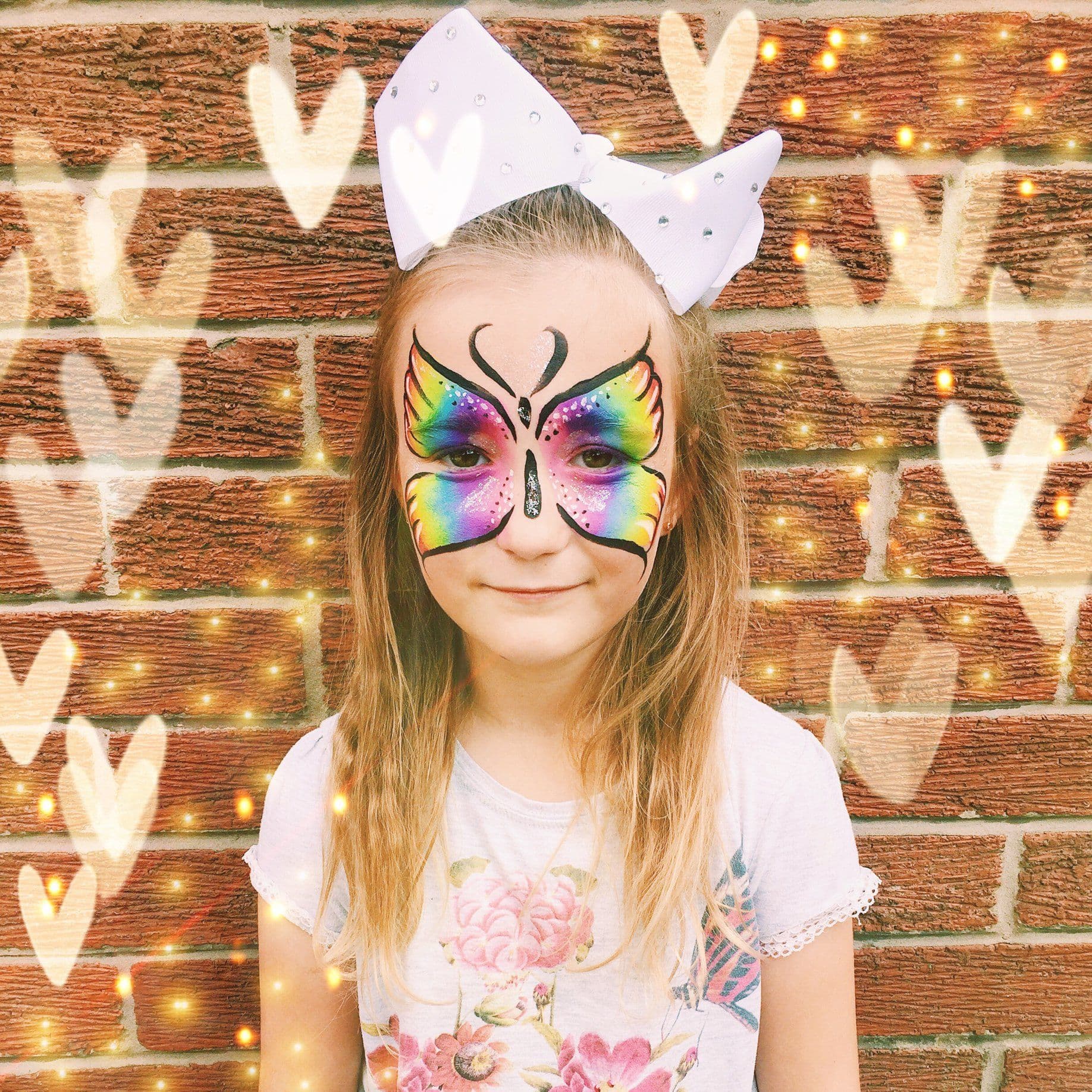 Rainbow butterfly face paint on a smiling girl
